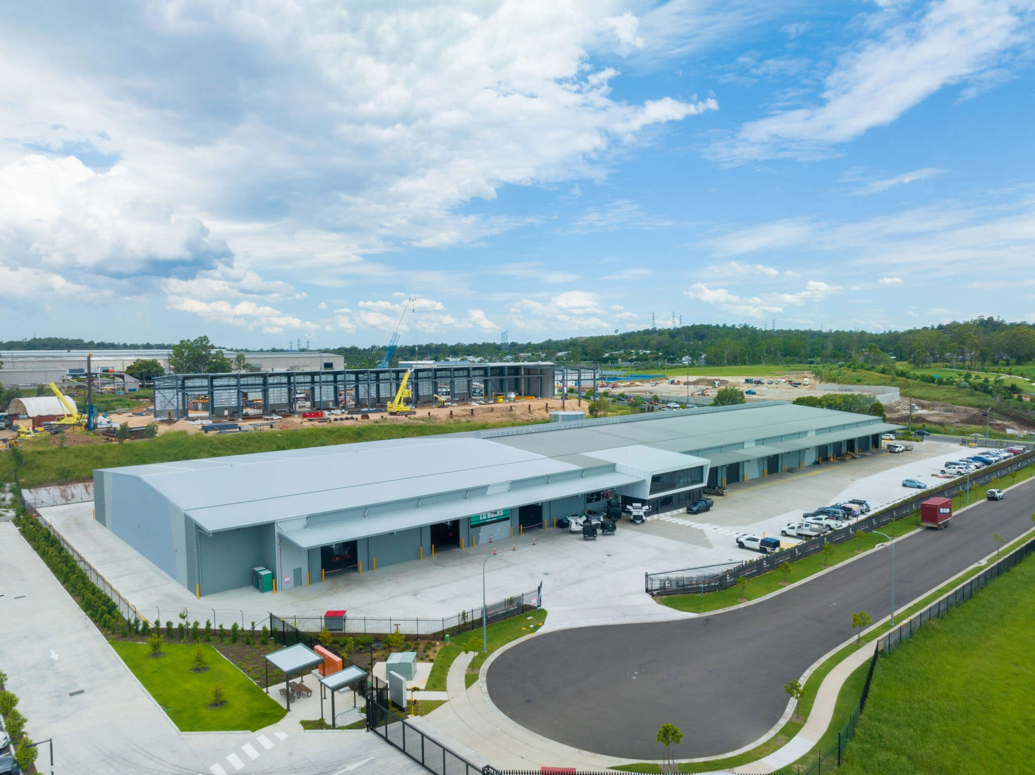 Aerial view of the Hume Drive warehouse, the completed steel-clad building in front of the bare frame of its extension under construction