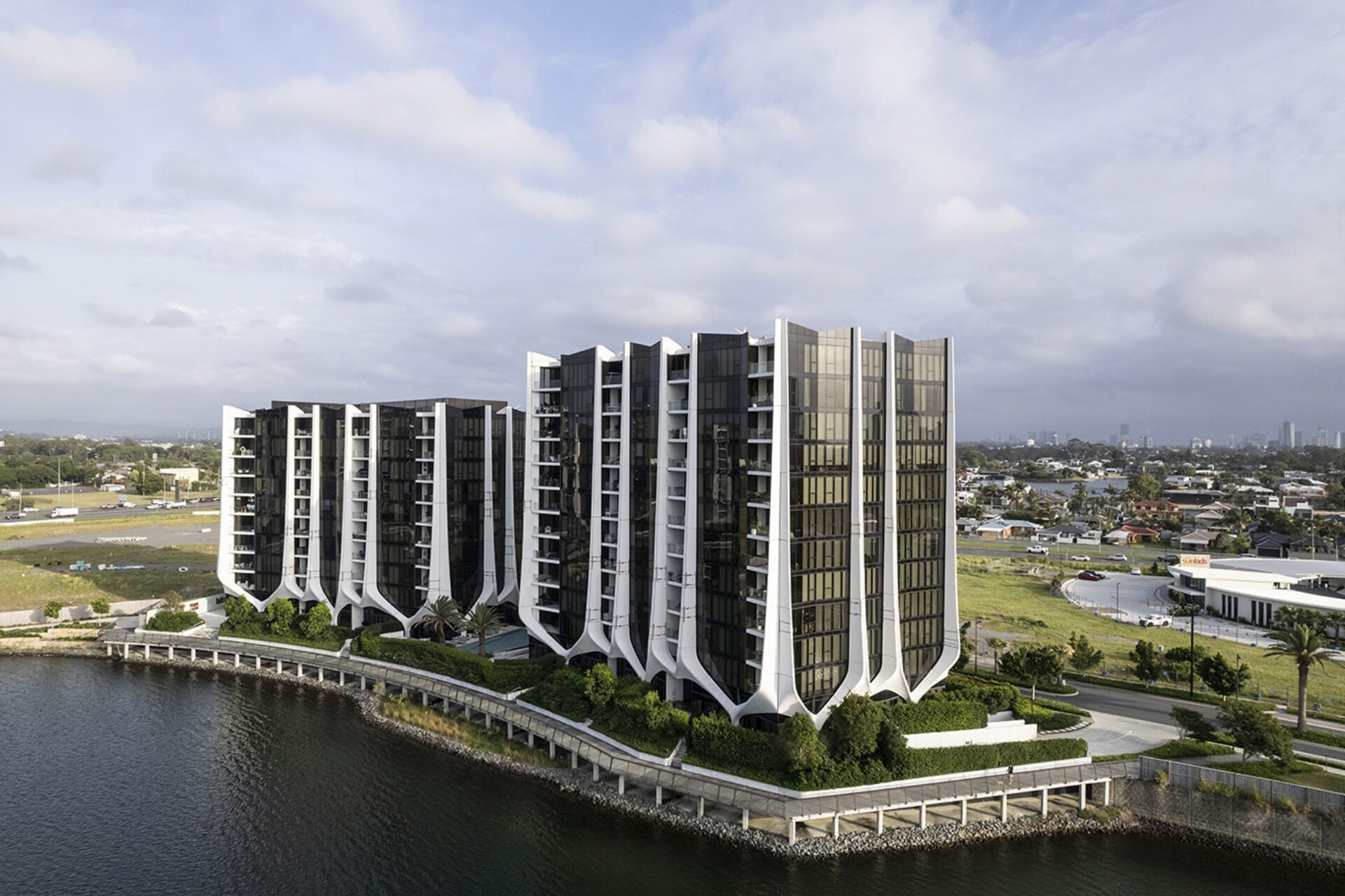 Aerial view of the Lanes Residences towers on the canal edge, white vertical fin blades between dark glazing