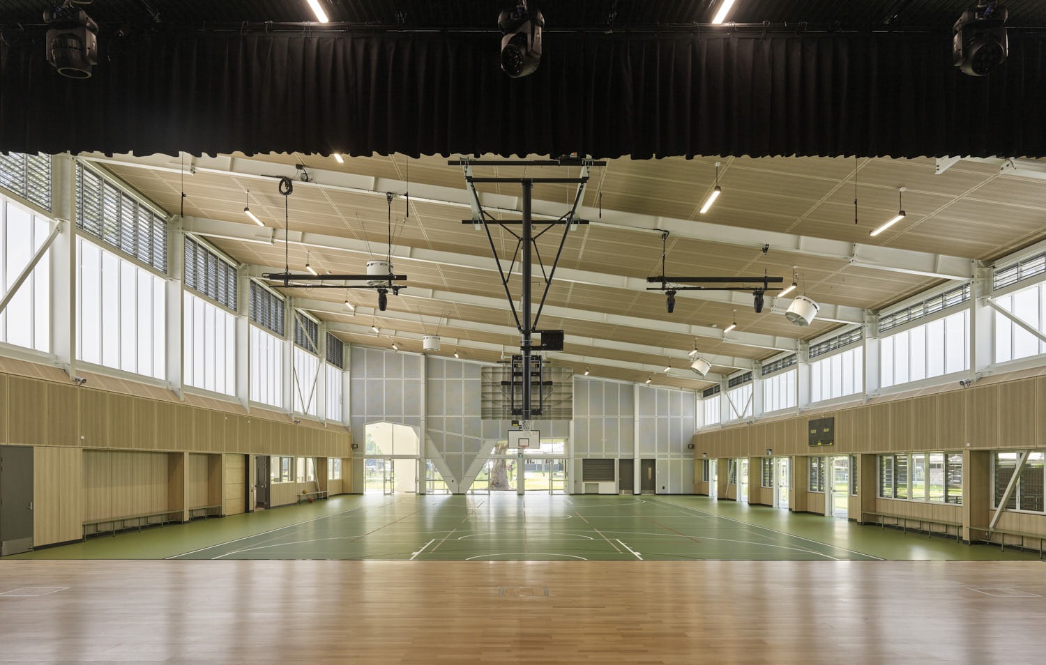 Interior of the Yandina State School multi-purpose hall, an indoor court under an exposed steel portal-frame roof with clerestory glazing